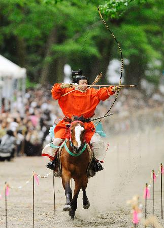 下鴨神社の「流鏑馬神事」で、疾走する馬上から矢を放つ射手=3日午後、京都市
